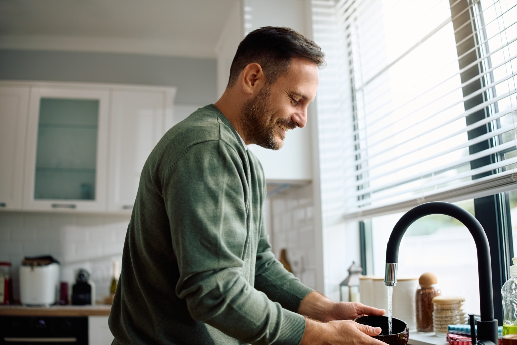smiling man washing dishes in kitchen